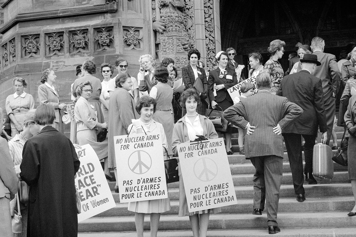 Duncan Cameron, <i>Femmes sur les marches du Parlement tenant des affiches « No Nuclear Arms for Canada ‒ Pas d’armes nucléaires pour le Canada »</i>, Montréal, 1961. Bibliothèque et Archives Canada, PA-209888