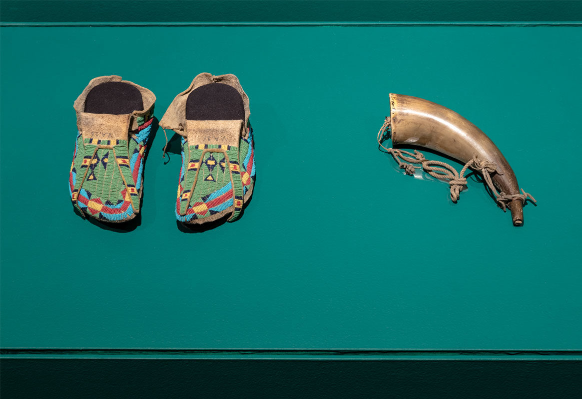 <i>Poundmaker’s Moccasins</i>, 1875-1890. Glass beads, painted rawhide from parfleche container, smoked brain-tanned buffalo hide. Collected by Walter Gouin from Chief Poundmaker, c.1875-1880. Canadian Museum of History.